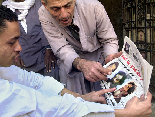 Egyptians Aladdin Al Gen, left, and Abdo Khalil, right, argue over identifying the pictures of the captured former Iraqi Saddam Hussein in Al- Messaa newspaper, Cairo, December 15, 2003