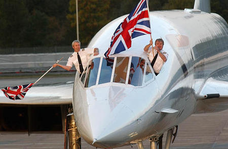 Captain Mike Bannister, right, and Senior First Officer Jonathan Napier wave and show the Union flag from the cockpit of their British Airways Concorde as it comes to its parking bay, after the last trans-Atlantic Concorde commercial flight, Heathrow Airport, London, October 24, 2003.