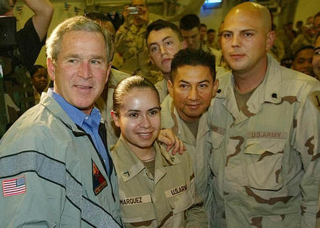 U.S. President George W. Bush stops to pose for photos with U.S. troops during his surprise visit for Thanksgiving at a military base at Baghdad International Airport, November 27, 2003.