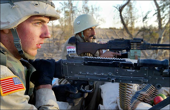 Army Specialist Robert Brown guards a checkpoint with Nativ Kazaum, of the Iraqi Civil Defense Corps, south of Tikrit, Iraq, mid November 2003.