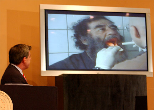 American administrator of Iraq L. Paul Bremer III watches video of captured former Iraqi leader Saddam Hussein undergoing mediacal examonations, Baghdad, December 14, 2003.