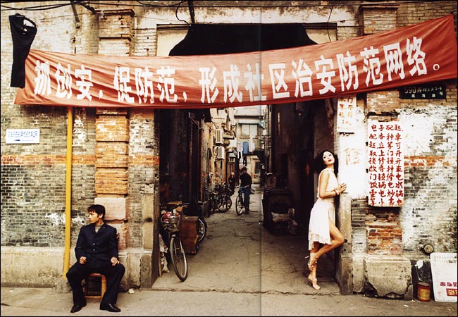 Model Qi Qi strikes a pose under a sign that reads 'Be careful of theft. Community security is important,' International Settlement, right off Wei Hai Lu, Shanghai, February 2004.