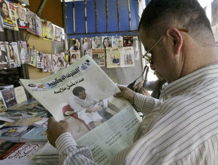 An Iraqi man in Baghdad reads A-Sharq Al-Awsat newspaper featuring a full front page picture of Saddam Hussein washing his clothes in prison, May 21, 2005.