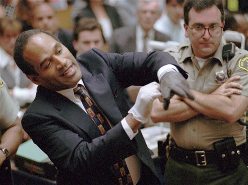 Defendant O.J. Simpson tries on one of the leather gloves prosecutors say he wore the night his ex-wife Nicole Brown Simpson and Ron Goldman were murdered, during the Simpson double-murder trial, Los Angeles, June 15, 1995.