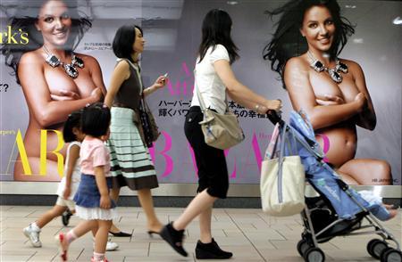 Mothers and their children walk past posters of a pregnant and nude Britney Spears in a subway station in Tokyo, Japan, August 28, 2006.