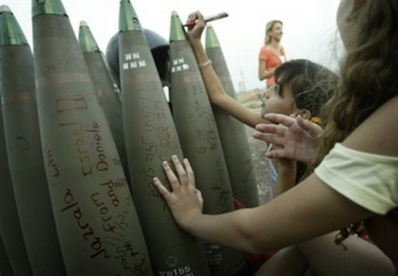 Israeli girls write messages on a shell at a heavy artillery position near Kiryat Shmona, in northern Israel, next to the Lebanese border, July 17, 2006.