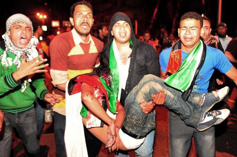 Demonstrators carry an injured man after severe police attack, in front of the Israeli Embassy, Dokki, Cairo, May 15, 2011.