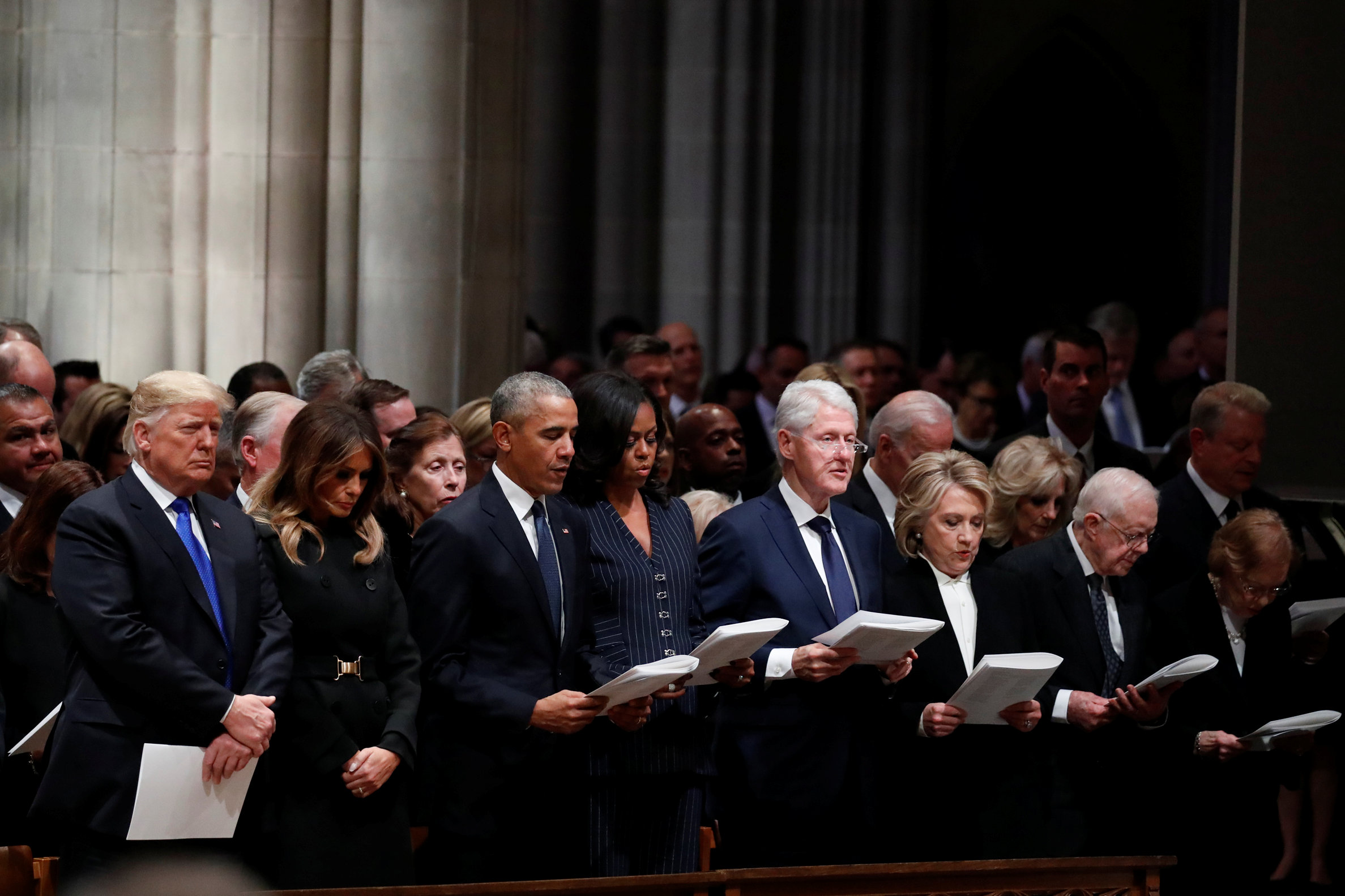 Donald and Melania Trump stand silent during George H.W. Bushs funeral as three former presidents and first ladies all recite the Apostles' Creed, Washington National Cathedral, December 5, 2018.
