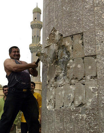 An Iraqi man swings a hammer at the base of the 40-foot statue of Saddam Hussein, central Baghdad, April 9, 2003.