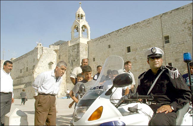 Residents admire a Palestinian police officer on a motorcycle, front of the Church of the Nativity, Bethlehem, July 2, 2003.