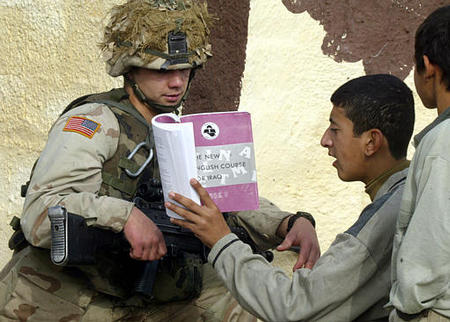 A U.S. soldier helps an Iraqi boy to learn English from 'The New English Course for Iraq,' a book American troops donated to children, Tikrit, Iraq, December 18, 2003.