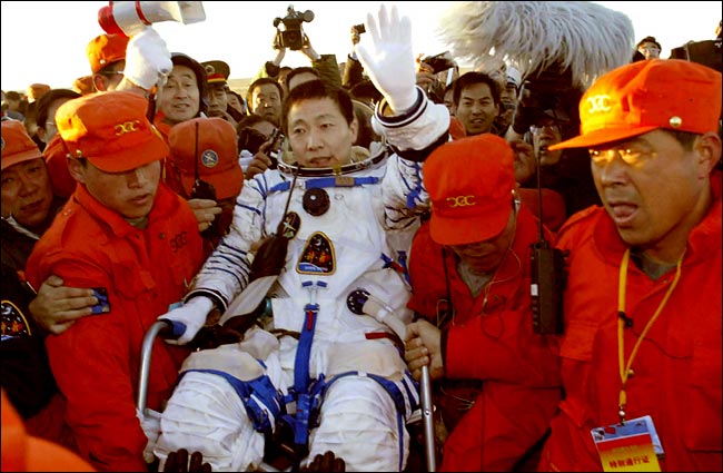 China's first astronaut Yang Liwei, 38, a lieutenant colonel of the People's Liberation Army, who piloted the Shenzhou V spacecraft, making China only the third country after the former Soviet Union and the United States to put a man into orbit, waved as Chinese soldiers carried him from his space capsule after it landed on grasslands of Inner Mongolia, China, October 16, 2003.