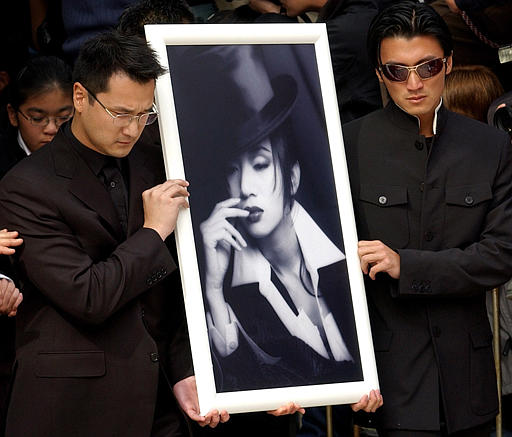 Hong Kong singer Nicolas Tse, right, and Anita Mui's cousin hold the picture of Canto-pop diva and actress Anita Mui outside the Collision crematorium after funeral service, to pay last tribute, Hong Kong, January 12, 2004.