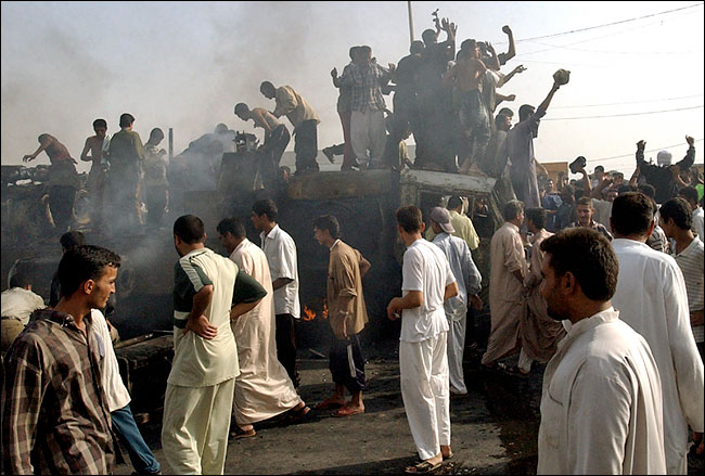 Iraqi youths cheered and danced atop an American Army truck after it was hit by an explosion and then set afire by Iraqis, Falluja, October 19, 2003.