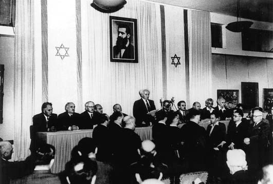 David Ben-Gurion, beneath a portrait of Theodore Herzl, founder of modern political Zionism movement, pronounces the Declaration of the Establishment of the State of Israel, Tel Aviv, May 14, 1948.