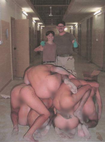 Two American soldiers pose next to a pyramid of naked Iraqi prisoners, at Abu Ghraib prison near Baghdad, in this undated photo released on April 30, 2004.