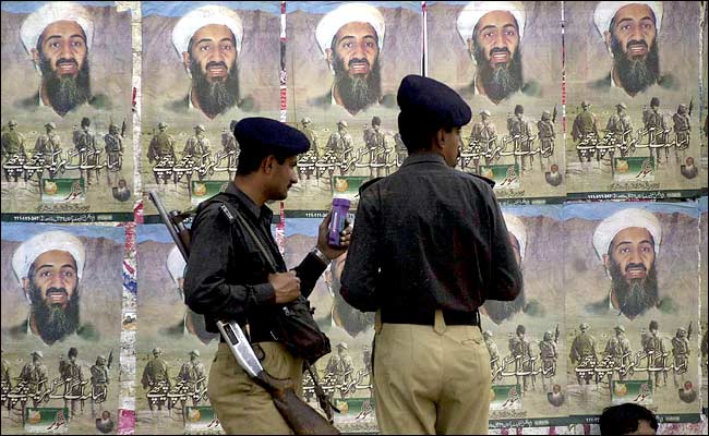 Pakistani Police soldiers pause near a row of posters of al Qaeda leader Osama bin Laden, Lahore, Pakistan, March 14, 2004.