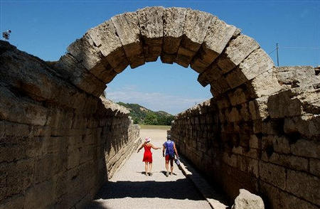 Tourists pass the entrance of the ancient stadium of Olympia, where the Olympics were born in 776 B.C., Greece, August 7, 2004.