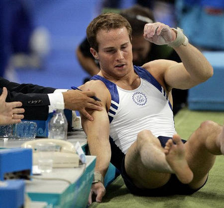 A judge reaches out to help Paul Hamm, of the United States, after he fell on the landing of his vault during the men's gymnastics individual all-around final at the 2004 Olympic Games in Athens, Greece, August 18, 2004.