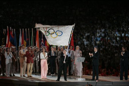 Beijing Mayor Wang Qishan waves the Olympic flag after receiving it from Athens Mayor Dora Bakoyiannis, cheered by Jacques Rogge, president of the International Olympic Committee, looks on at right, Gianna Angelopoulos-Daskalaki, president of the Athens 2004 Organizing Committee, left, Hicham A-Guerrouj of Morocco, with a red jacket and Rania Elwani of Egypt, the woman with headscarf, during the closing ceremony of the 2004 Summer Olympics in the Olympic Stadium in Athens, August 29, 2004.