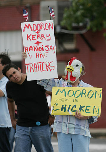 Carol Jones of Austin, a supporter of President Bush, holds signs while dressed as a chicken during a rally in Crawford, Texas, July 28, 2004.