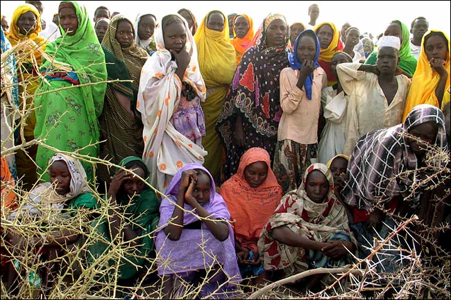 Displaced women and children outside a camp in the Darfur region of Sudan, waiting to receive rations distributed by the World Food Program, April 2004.