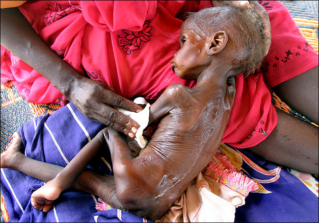 A mother held her ill daughter at a Doctors Without Borders clinic near Nyala, Sudan, where violence and disease are killing tens of thousands, July 2004.