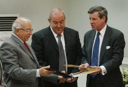 U.S. Administrator L. Paul Bremer III hands over documents to Iraqi Chief Justice Medhat al-Mahmodi, left, transferring national sovereignty to Iraq while Iraqi Prime Minister Iyad Allawi watching at a ceremony, Baghdad, Iraq, June 28, 2004.
