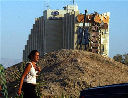 Following an explosion the night before, an Isaraeli tourist walks past the damaged Taba Hilton Hotel, Taba, Egypt, October 8, 2004.