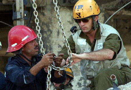 Egyptian and Israeli rescuers, tie chains around part of the debris of the damaged Taba Hilton Hotel, Taba, Egypt, October 9, 2004.