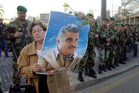 A Beirut resident holds a portrait of former Prime Minister Rafiq l-Hariri as soldiers line the streets during a demonstration protesting his assassination, Beirut, Lebanon, February 14, 2005.
