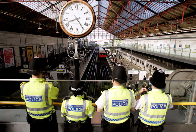 Police keep watch over passengers during morning rush hour at Earls Court Station, London, August 4, 2005.
