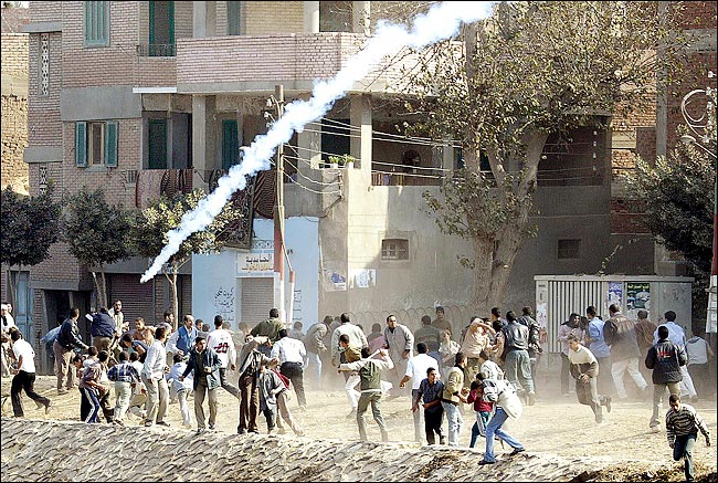 Egyptians flee tear gas fired by policemen at a voting site in Zagazig, December 7, 2005.