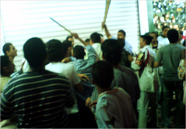 Store owners try to fight off young men who had surrounded a victim of groping, Cairo, Egypt, October 2006.