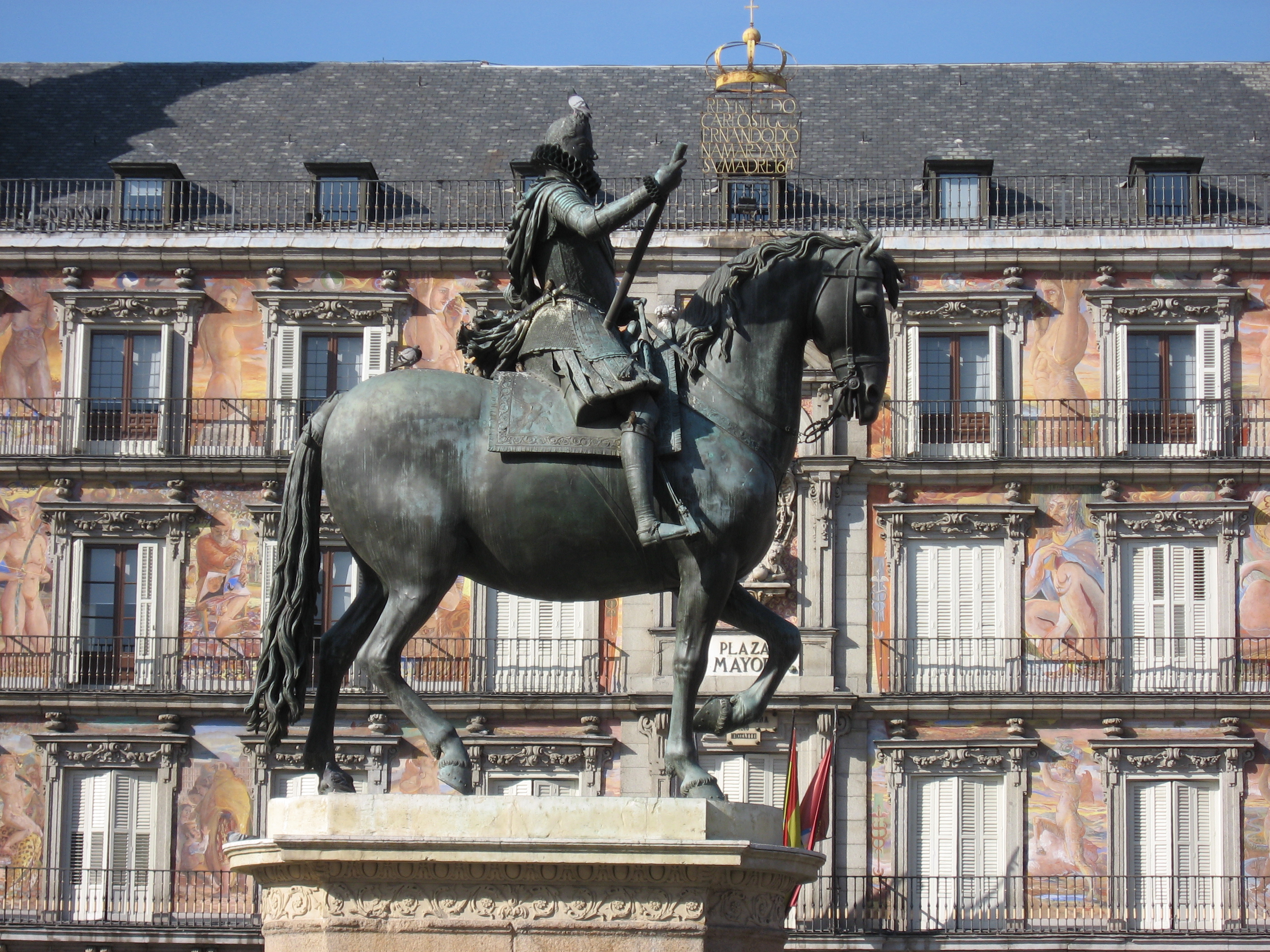 Statue of King Philip III in front of its bright red facades of Plaza Major, Madrid, Spain.