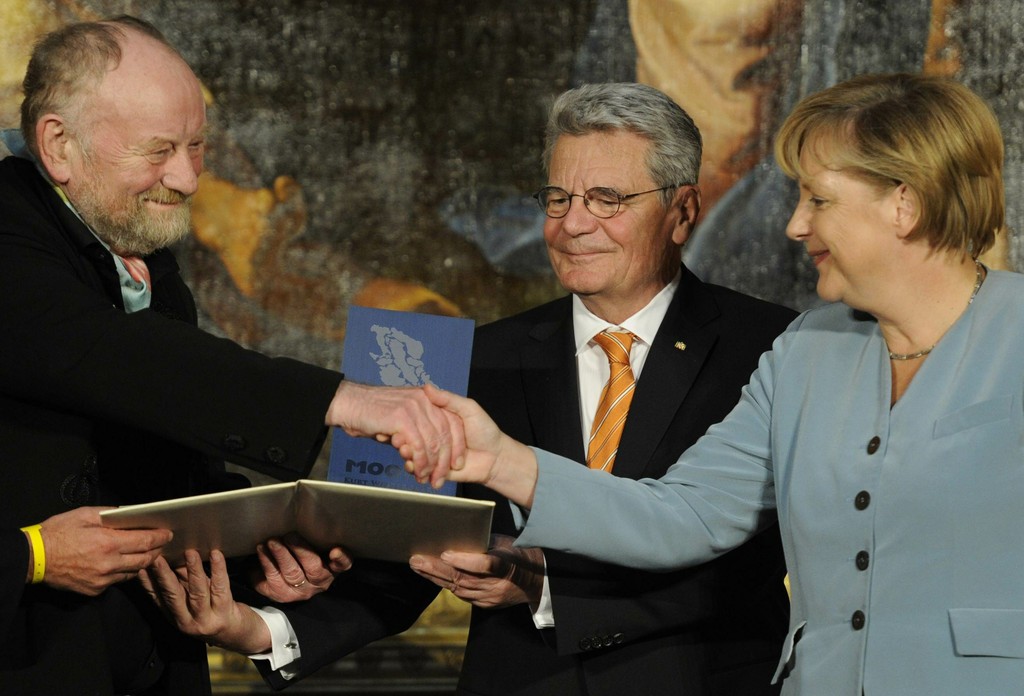 German Chancellor Angela Merkel congratulates Danish cartoonist Kurt Westergaard, who in 2005 drew the most controversial of 12 caricatures of the Prophet Muhammad, on receiving the M100 Media Prize 2010, as the former head of the state-funded body which manages the archives of the former East German secret police Stasi Joachim Gauck and Potsdam's mayor Jann Jakobs, not seen, look in, Potsdam, near Berlin, eastern Germany, September 8, 2010.