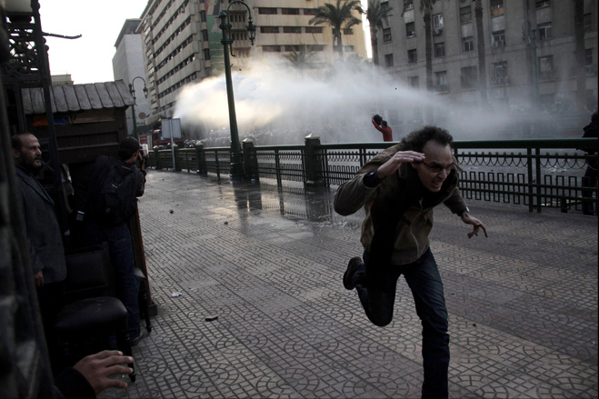 A demonstrator runs away water cannons used by riot police, downtown Cairo, Egypt, January 25, 2011.