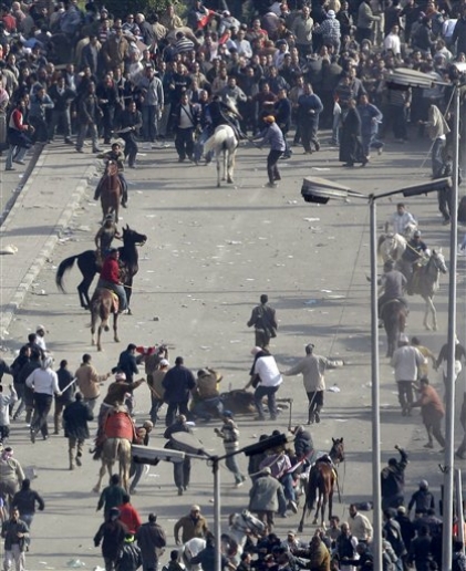 Pro-government demonstrators, below, surround a fallen horse and rider, as others, some riding camels and horses and armed with sticks, clash with anti-government demonstrators, above, in A-Tahrir Square, the center of anti-government demonstrations, in Cairo, Egypt, February 2, 2011.