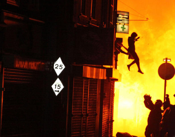 A woman jumps from a burning building in Surrey Street after rioting took place in Croydon, London, August 8, 2011.