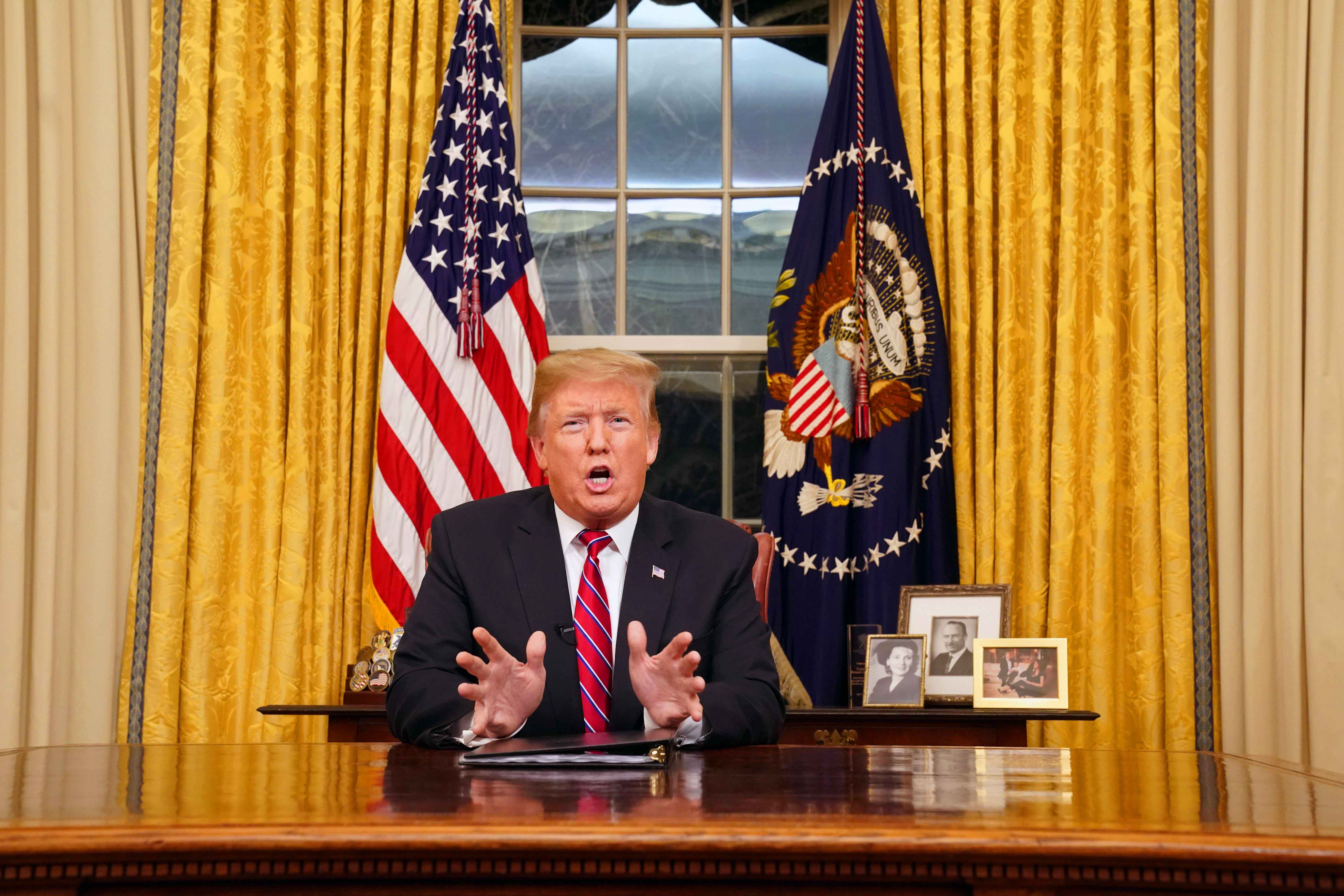 In front of his collection of military challenge coins, a portrait of his mother Mary Anne Trump, his father Fred Trump and his wife Melania and their son Barron, the U.S. President Donald Trump delivers a televised address to the nation from his desk in the Oval Office about immigration and the southern U.S. border on the 18th day of a partial government shutdown at the White House in Washington, U.S., January 8, 2019.