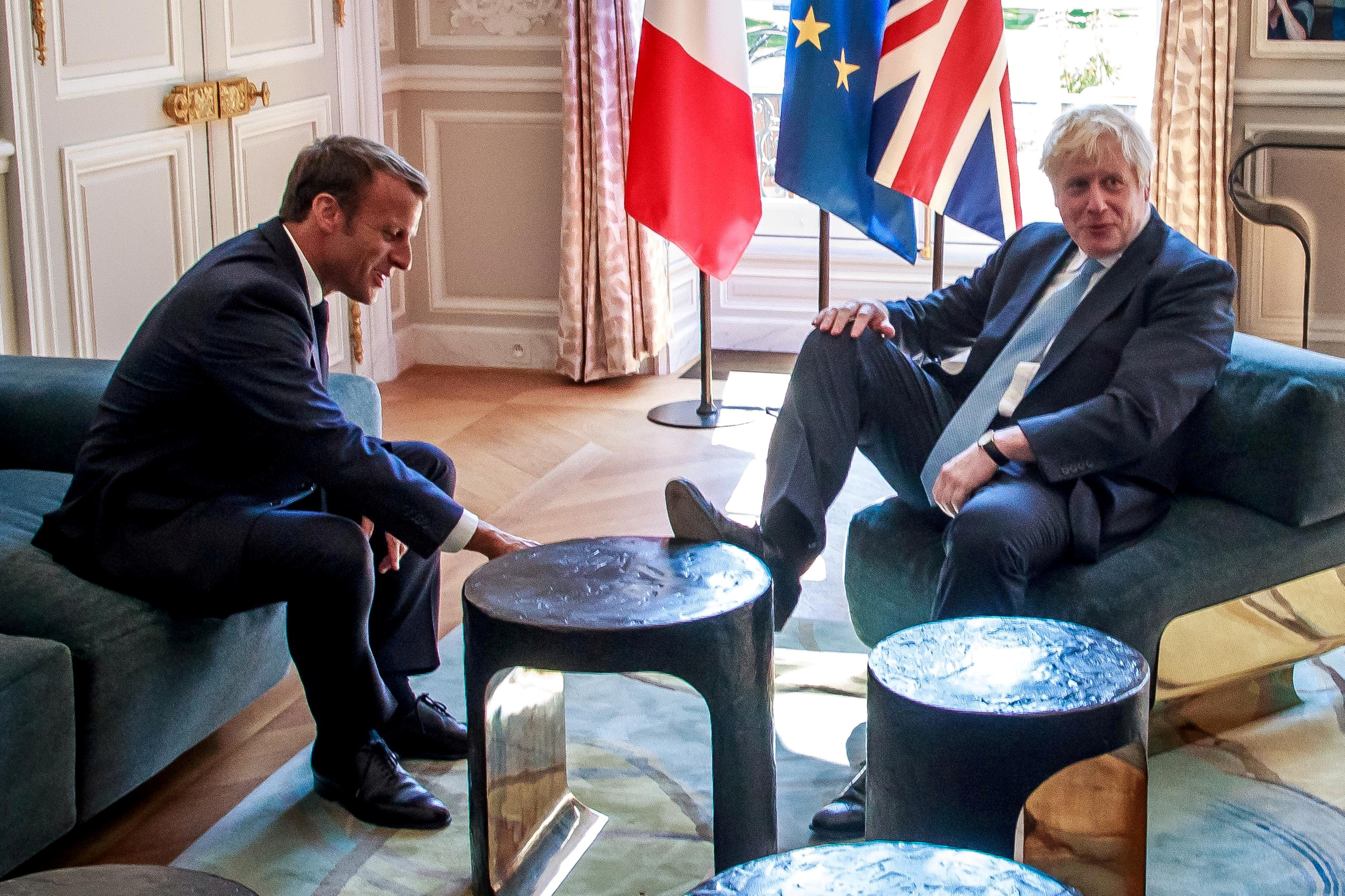 UK Prime Minister Boris Johnson puts his foot on table as French President Emmanuel Macron watching in, Palace of l'Élysée Paris, August 22, 2019.